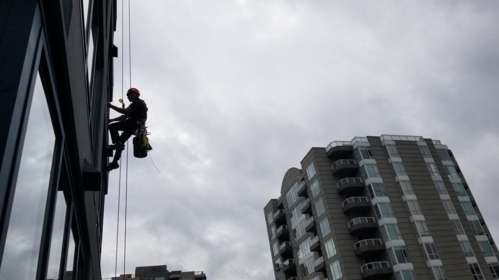 Hooked into a harness for rope access building work | Granite